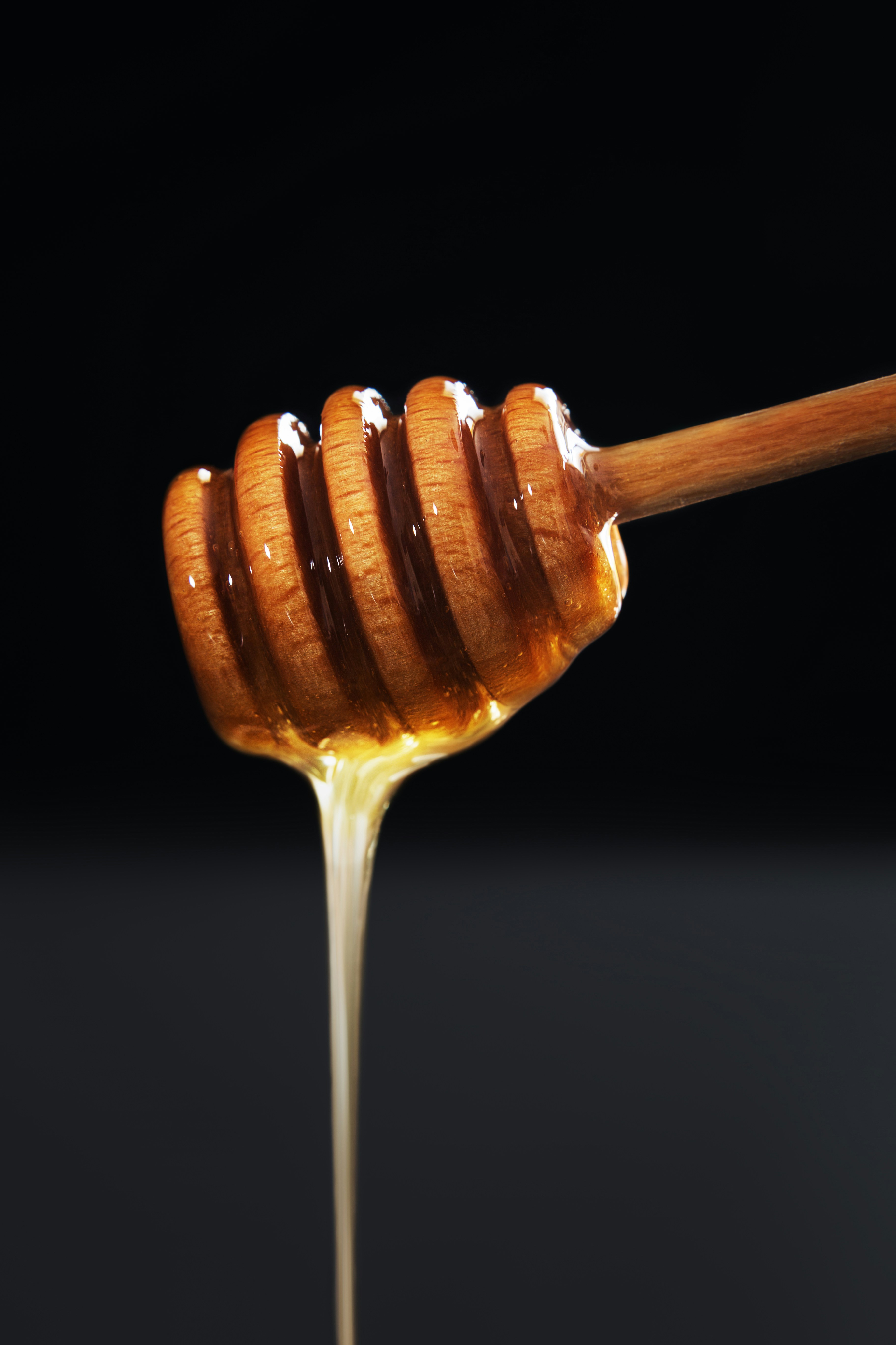 Golden honey being drizzled from a honey dipper.